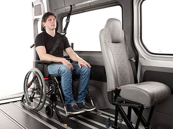 Person seated in a wheelchair with occupant and wheelchair restraints