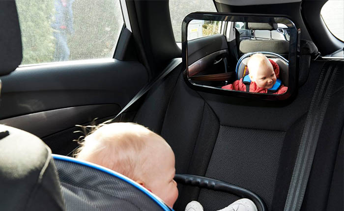 Baby sitting in a car looking into a mirror