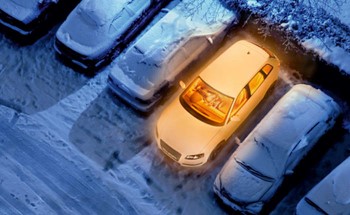 Aerial view of cars covered in snow and one car heated without snow