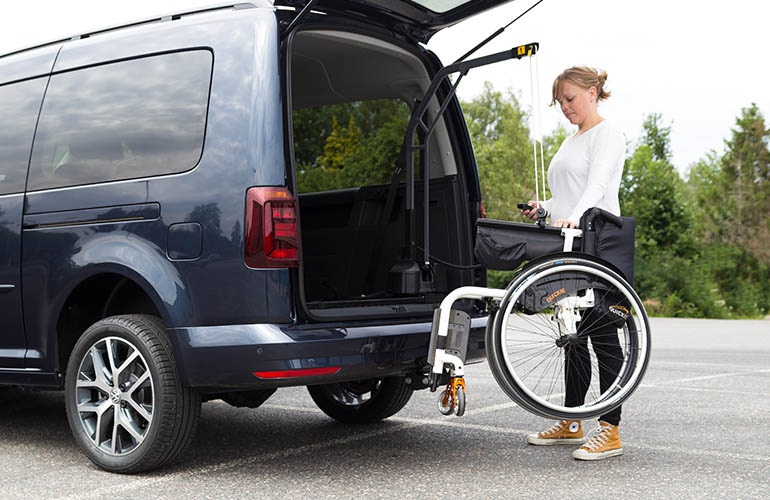 Woman hoisting a wheelchair into a car with a Carolift 90