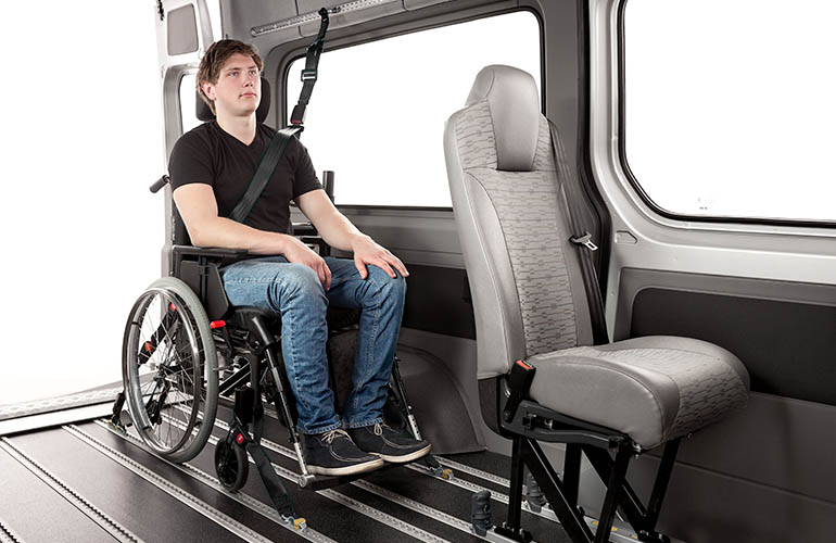 A teenager sitting in a wheelchair inside a van.