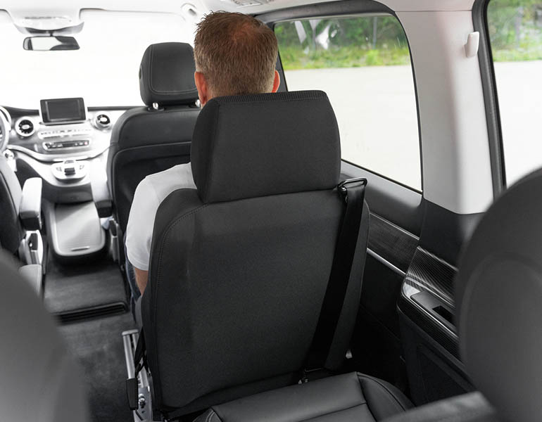 Inside view of a minivan showing a man seated in the second row from behind.