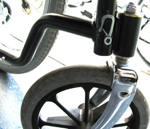 Symbole de mousqueton sur le châssis du fauteuil roulant.