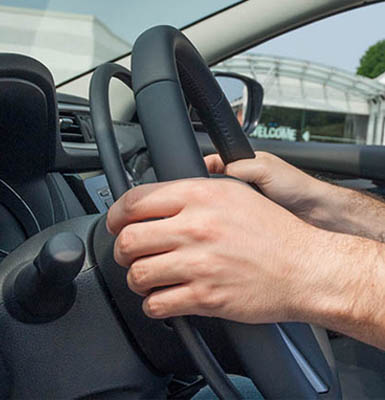 Hands holding a steering wheel with a gas ring. 