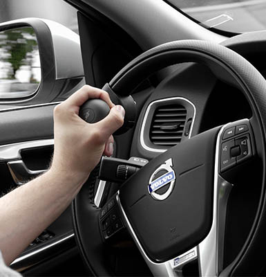 One hand holding a steering wheel by the steering device. 