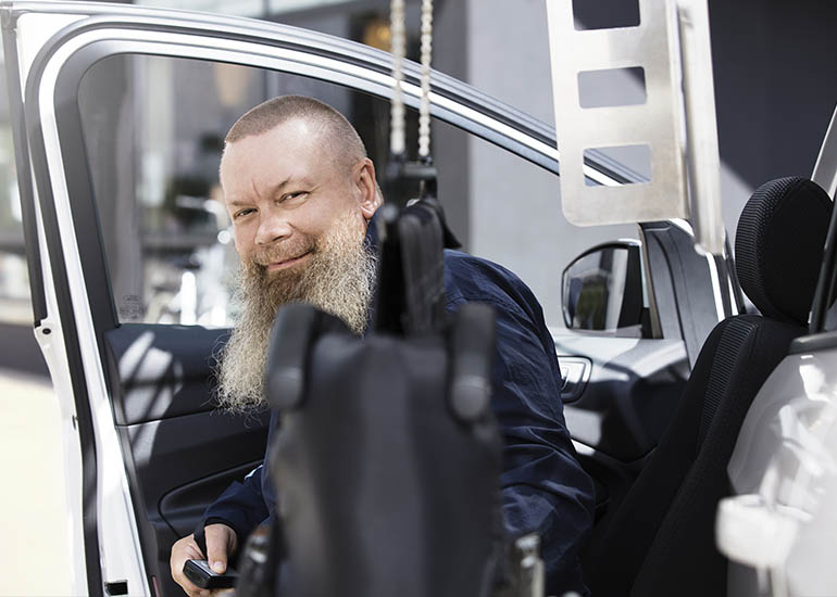 Homme souriant derrière un fauteuil roulant récupéré d'un topper de chaise