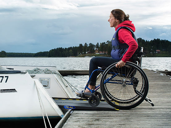 Woman on a wheelchair rolling over a ramp to get into a boat