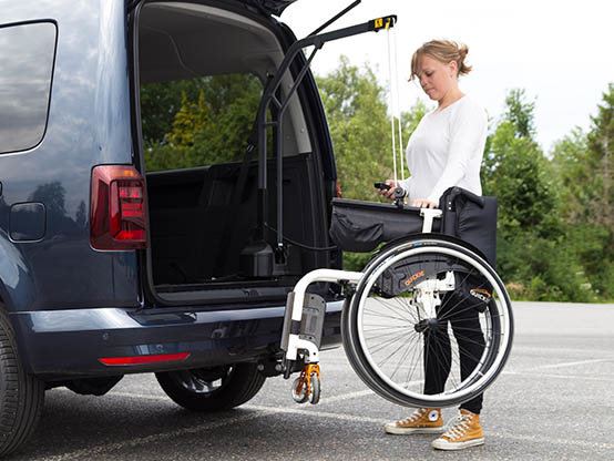 Woman hoisting a wheelchair into a car with a Carolift 90